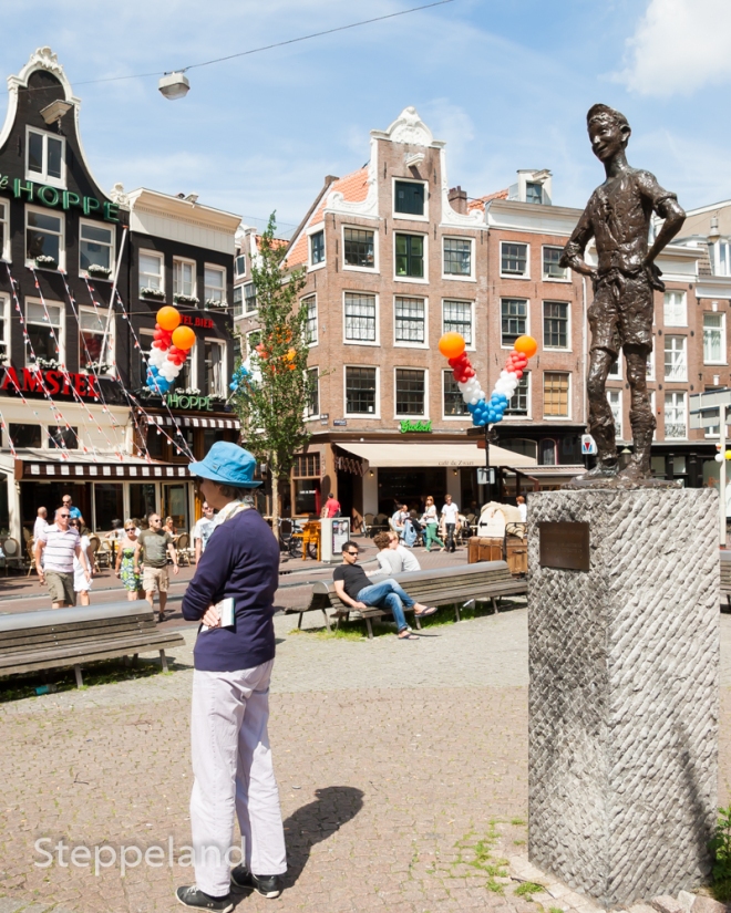Lady with blue hat is turning her back to "het Amsterdams Lieverdje" (the Amsterdam sweetheart) - statue on Spui square
