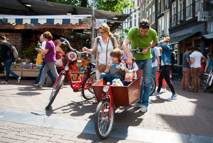 Family, mom dad and kids, with red bicycles eating salted chips - Amsterdam Street photography